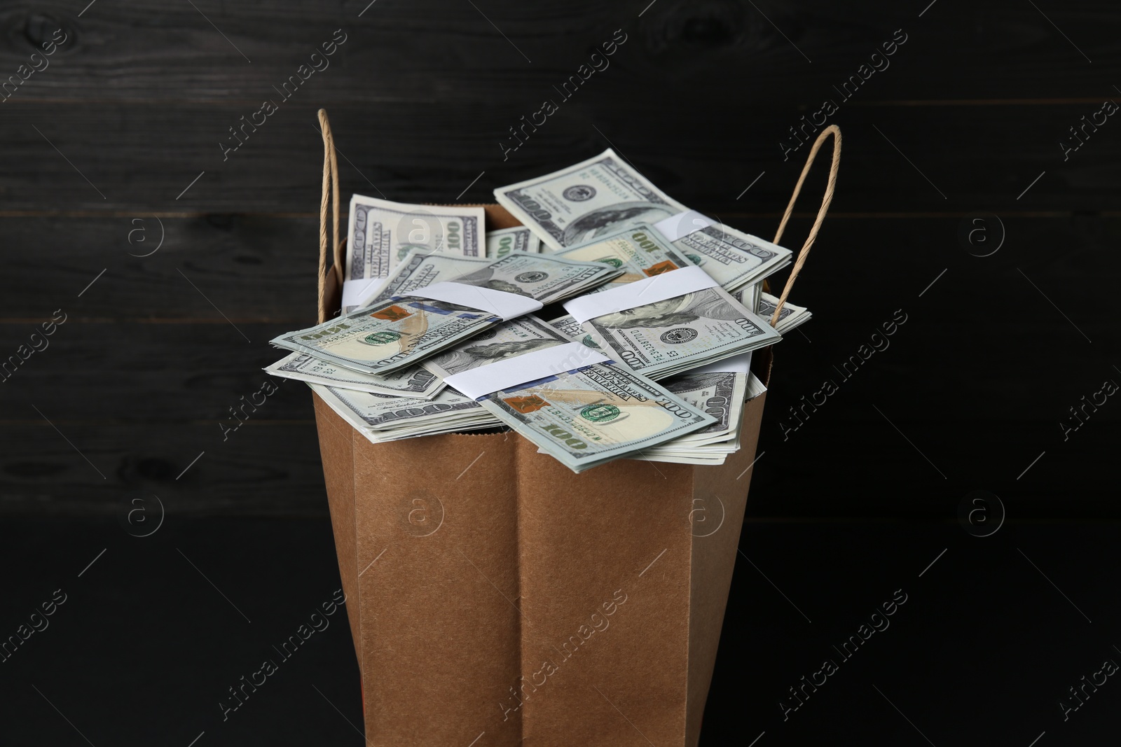 Photo of Dollar banknotes in paper bag on black table, closeup