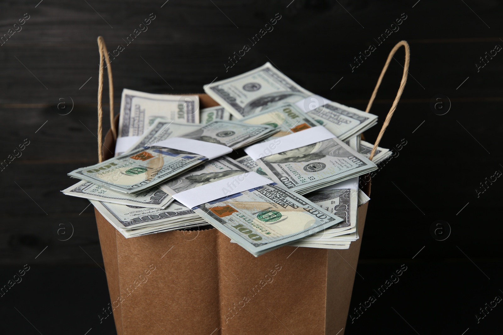 Photo of Dollar banknotes in paper bag on table, closeup