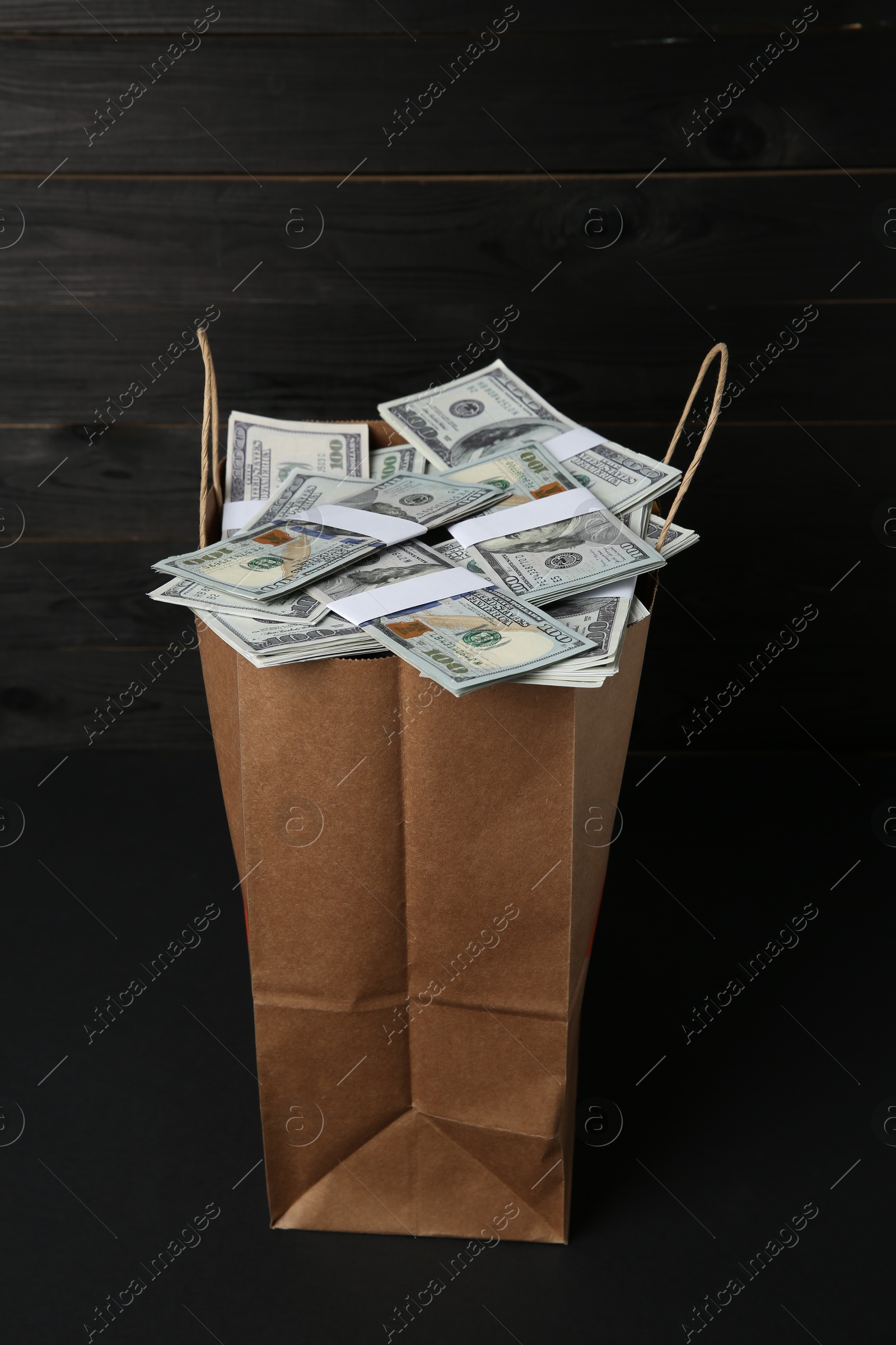 Photo of Dollar banknotes in paper bag on black table