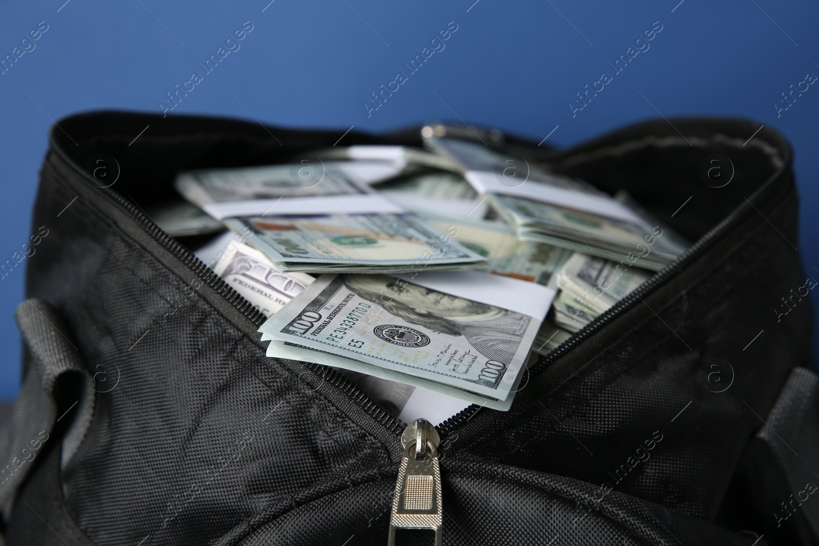 Photo of Dollar banknotes in bag on blue background, closeup