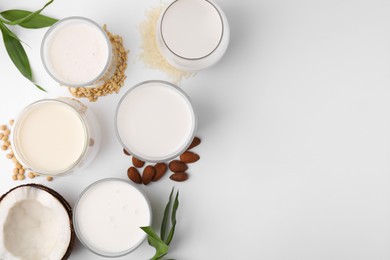 Photo of Different types of vegan milk and ingredients on white table, flat lay. Space for text