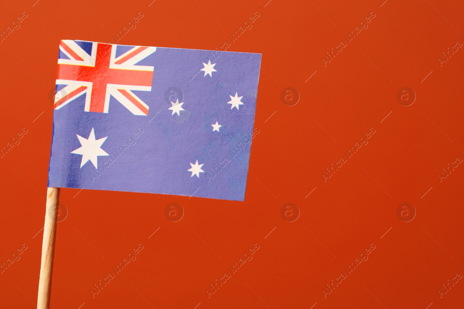 Photo of Small paper flag of Australia on orange background, space for text