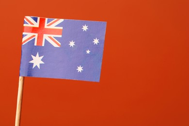 Photo of Small paper flag of Australia on orange background, space for text