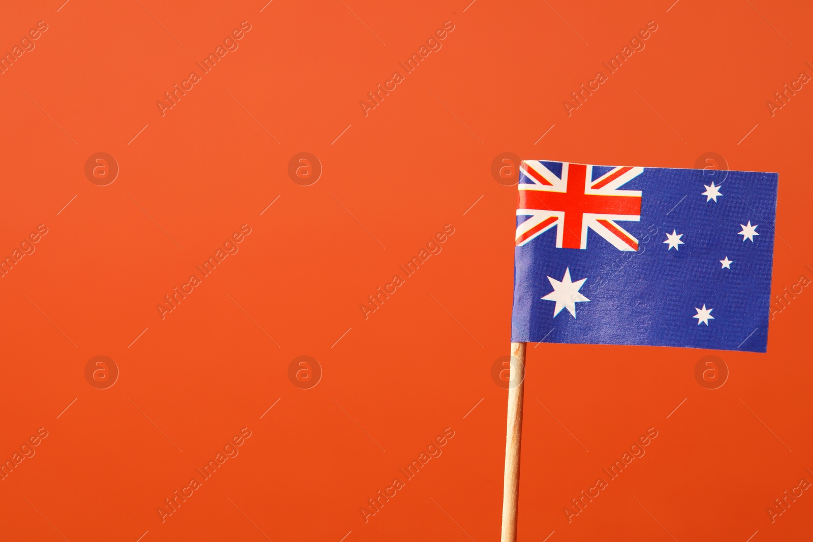 Photo of Small paper flag of Australia on orange background, space for text