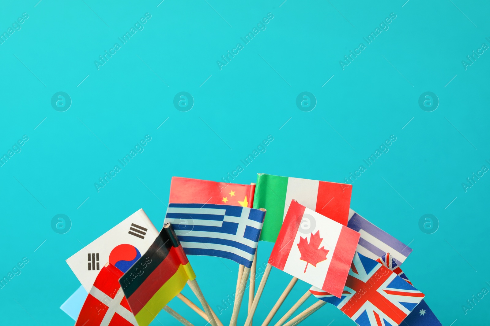 Photo of Small paper flags of different countries on light blue background