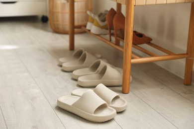 Many pairs of slippers and other shoes in entryway at home