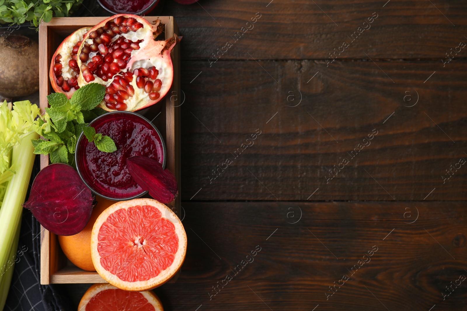 Photo of Glass of tasty beetroot smoothie, fresh vegetables, fruits and mint in box on wooden table, top view with space for text. Vegan drink