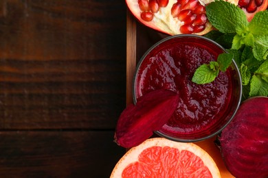 Photo of Glass of tasty beetroot smoothie, fresh vegetables, fruits and mint in box on wooden table, top view with space for text. Vegan drink