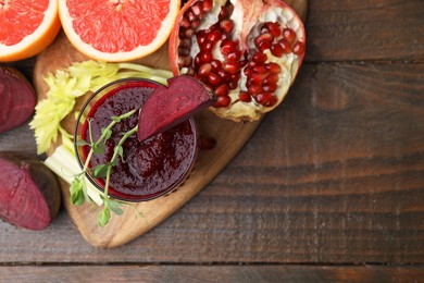 Photo of Tasty beetroot smoothie in glass, microgreens, fresh vegetables and fruits on wooden table, top view with space for text. Vegan drink