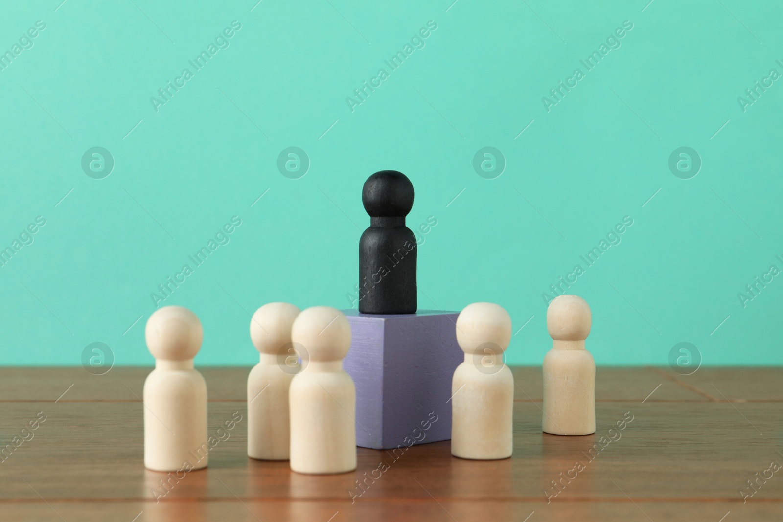 Photo of Black piece among wooden ones on table against turquoise background