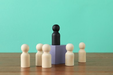 Photo of Black piece among wooden ones on table against turquoise background