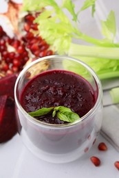 Fresh beetroot smoothie with mint in glass on white table, closeup