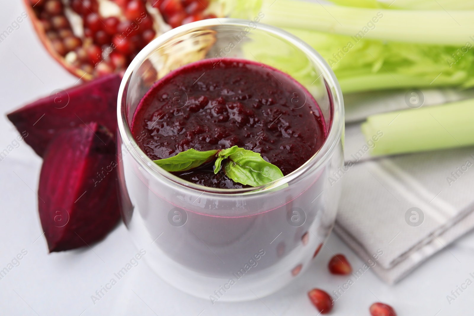 Photo of Fresh beetroot smoothie with mint in glass on white table, closeup