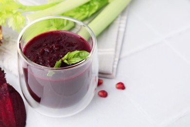 Fresh beetroot smoothie with mint in glass on white tiled table. Space for text