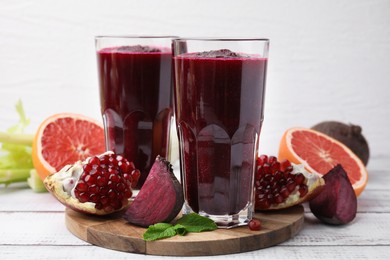 Fresh beetroot smoothie in glasses, grapefruit, beet and pomegranate on white wooden table