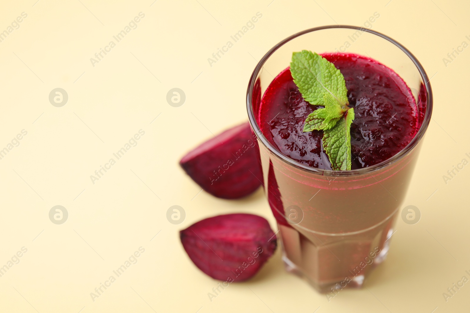 Photo of Fresh beetroot smoothie with mint in glass on beige background, closeup. Space for text