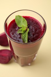 Photo of Fresh beetroot smoothie with mint in glass on beige background, closeup