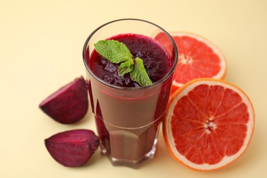 Photo of Fresh beetroot smoothie in glass, grapefruit and beet on beige background