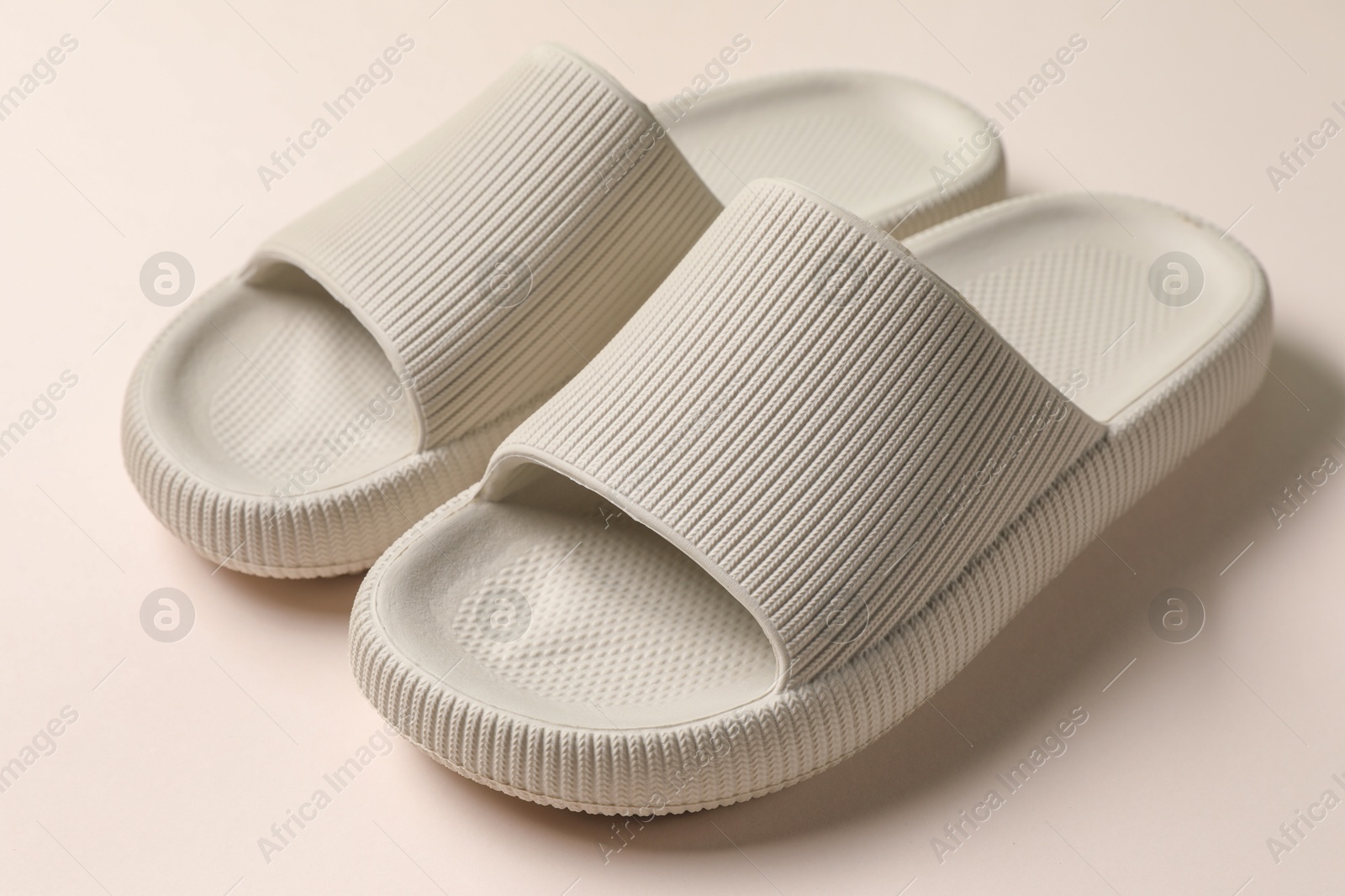 Photo of Pair of rubber slippers on beige background, closeup