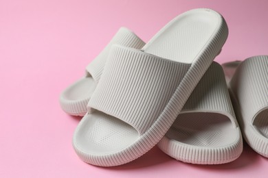 Photo of Pairs of rubber slippers on pink background, closeup