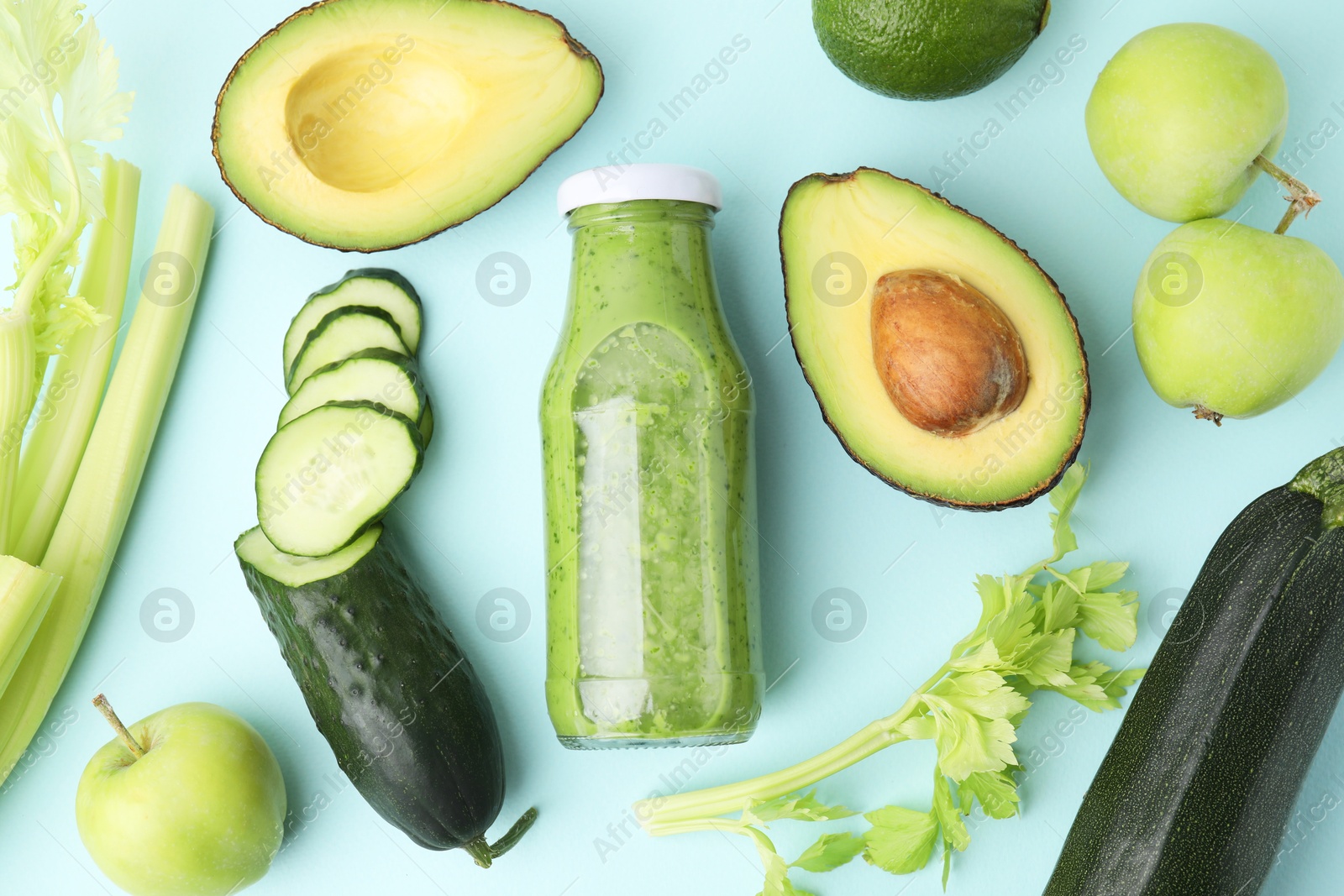 Photo of Flat lay composition with tasty green smoothie in bottle and products on light blue background