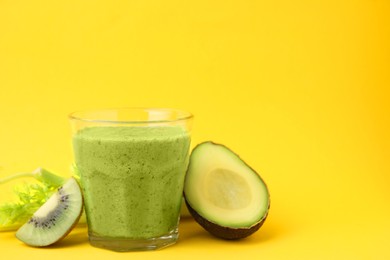 Photo of Delicious green smoothie and ingredients on yellow table. Space for text