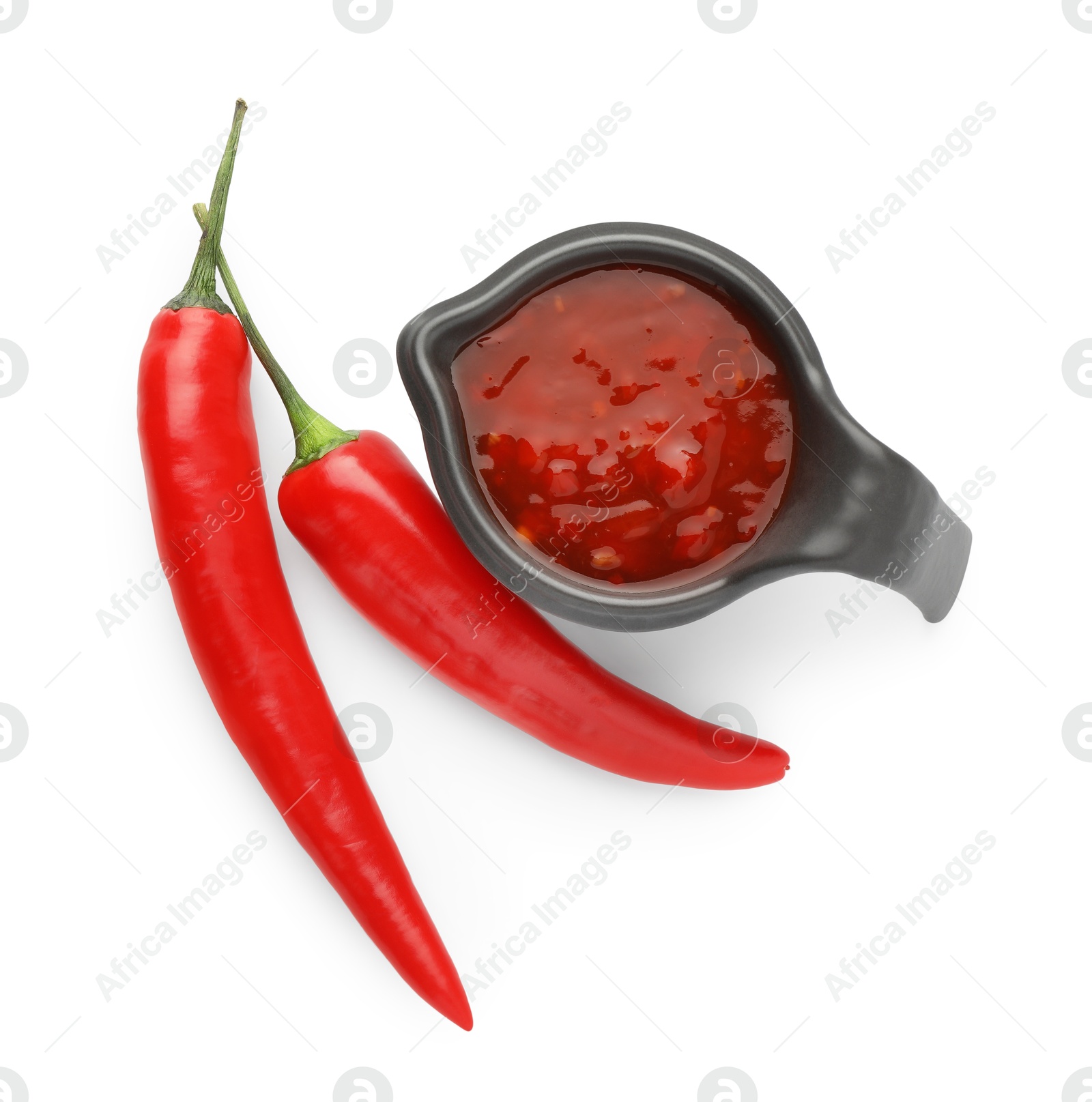 Photo of Hot chili sauce in gravy boat and peppers isolated on white, top view