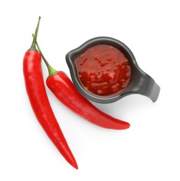 Photo of Hot chili sauce in gravy boat and peppers isolated on white, top view