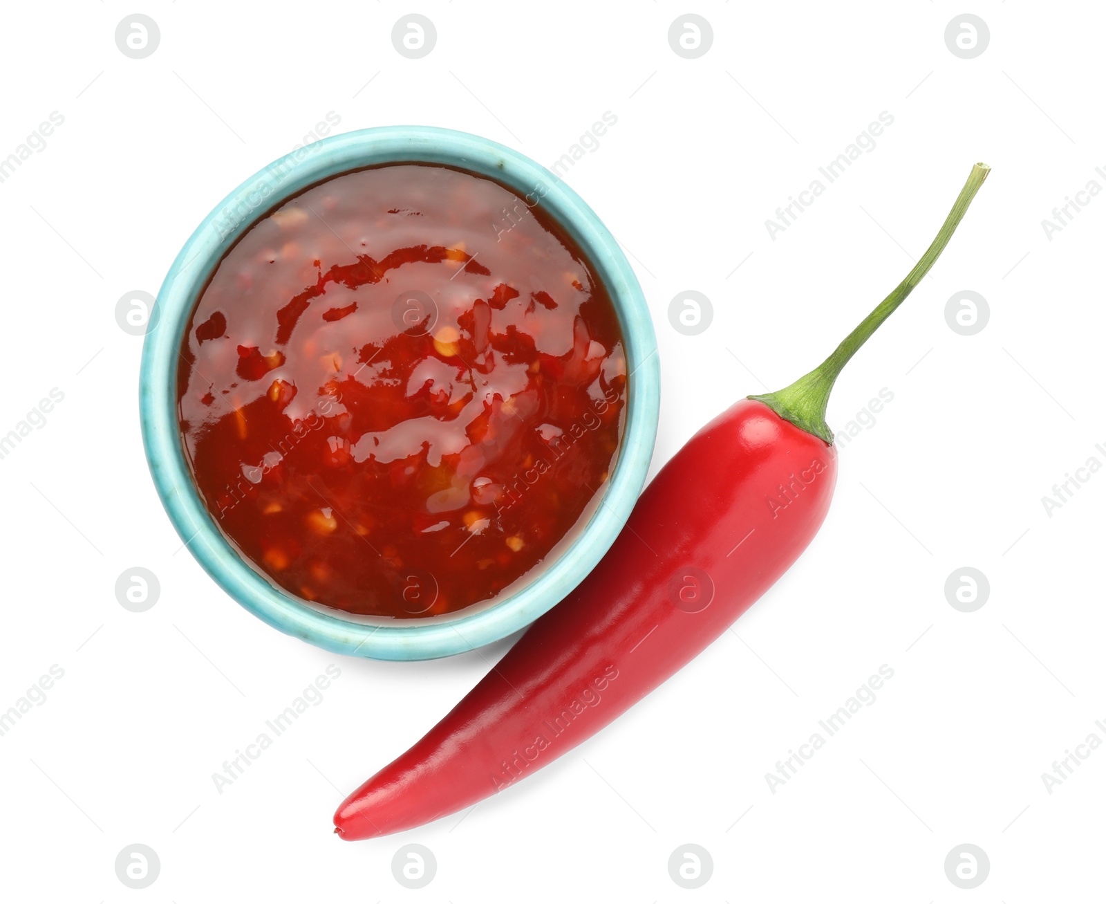 Photo of Hot chili sauce in bowl and pepper isolated on white, top view