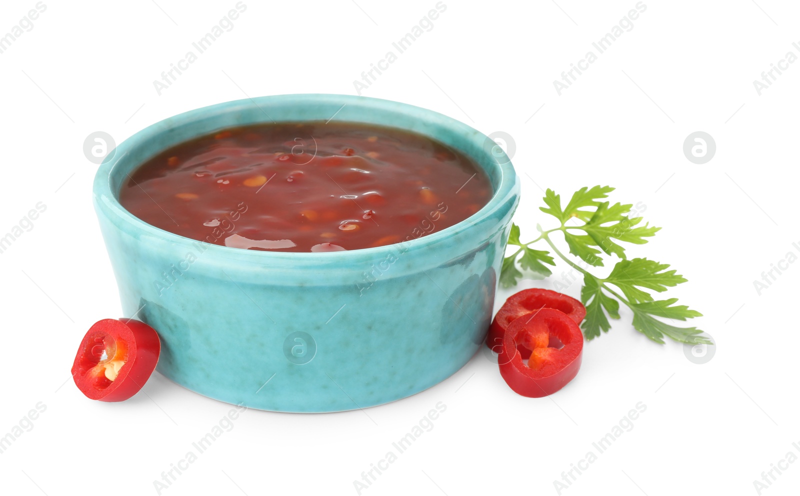 Photo of Hot chili sauce in bowl, parsley and cut pepper isolated on white