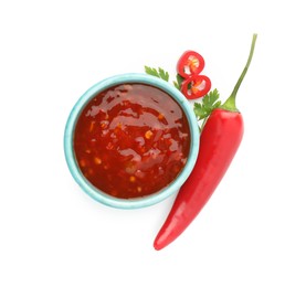 Photo of Hot chili sauce in bowl, parsley and pepper isolated on white, top view