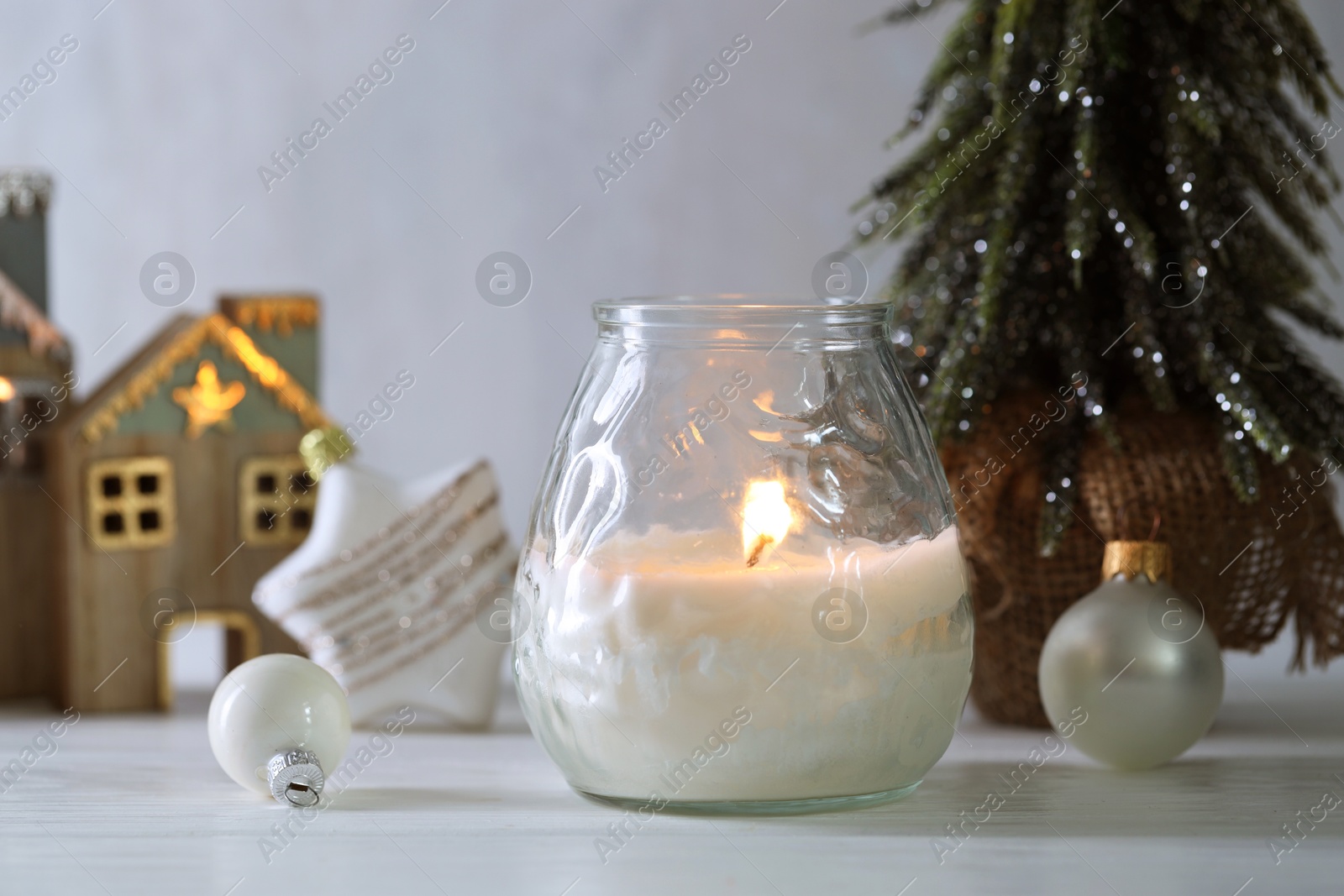 Photo of Burning candle and Christmas decor on white wooden table, closeup