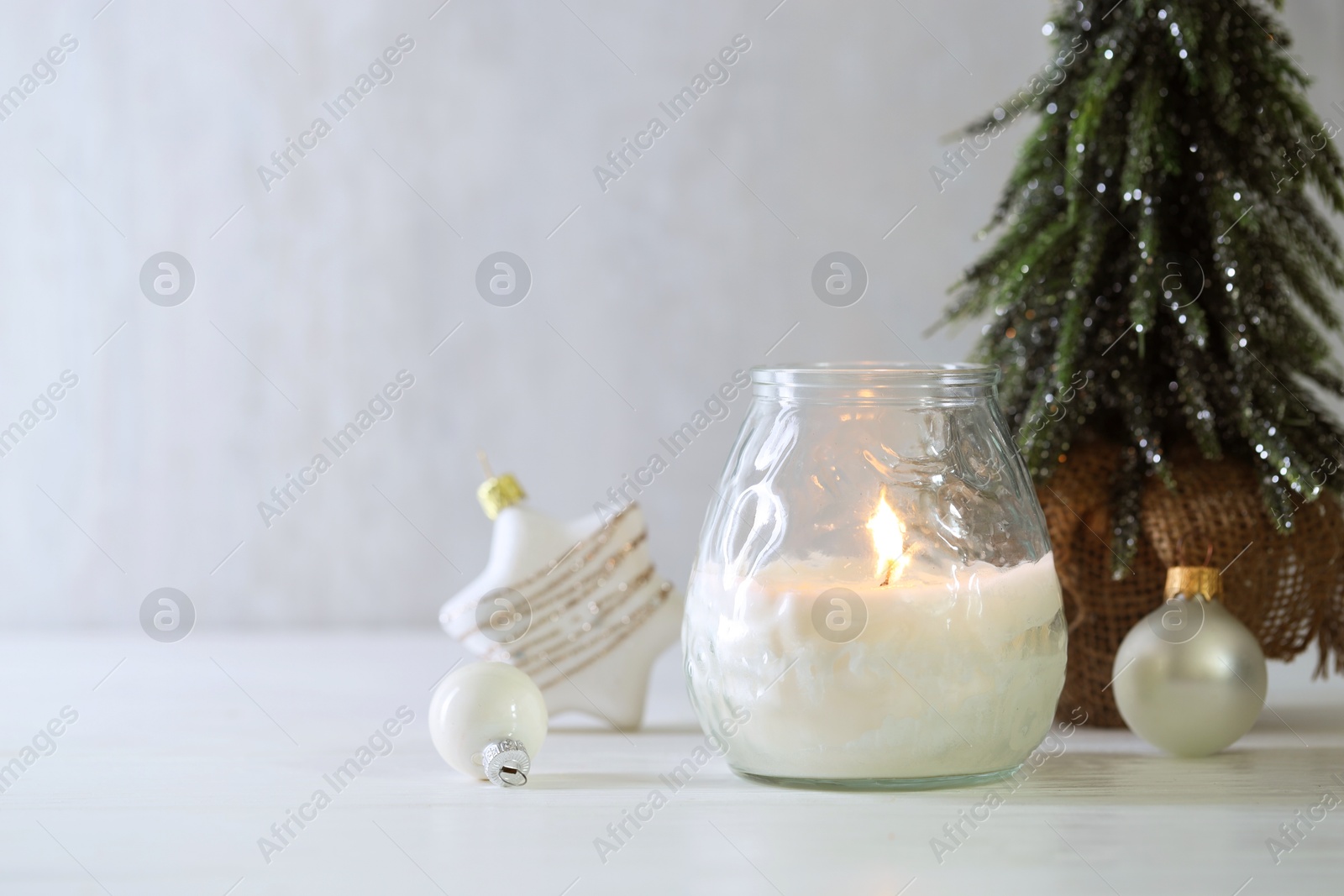 Photo of Burning candle and Christmas decor on white wooden table, closeup. Space for text