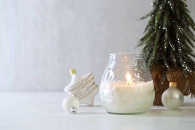 Photo of Burning candle and Christmas decor on white wooden table, closeup. Space for text