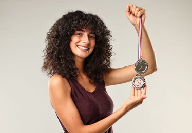 Happy winner with different medals on light grey background