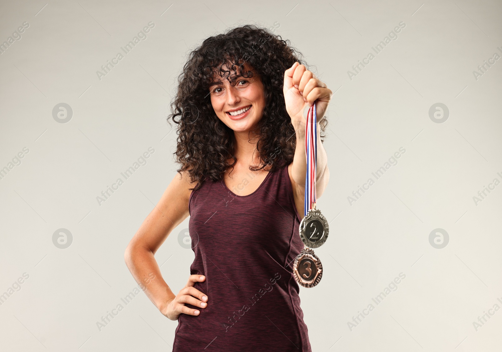 Photo of Happy winner with different medals on light grey background