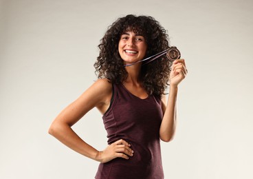 Photo of Happy winner with bronze medal on light grey background