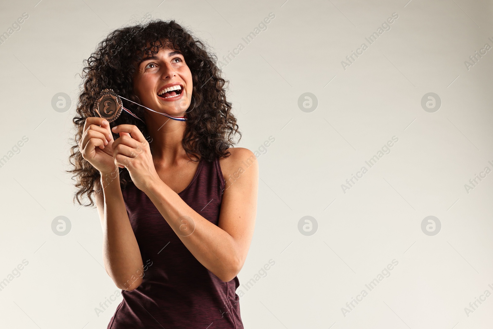 Photo of Happy winner with bronze medal on light grey background. Space for text