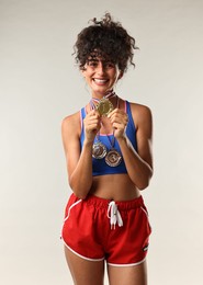 Photo of Happy winner with different medals on light grey background