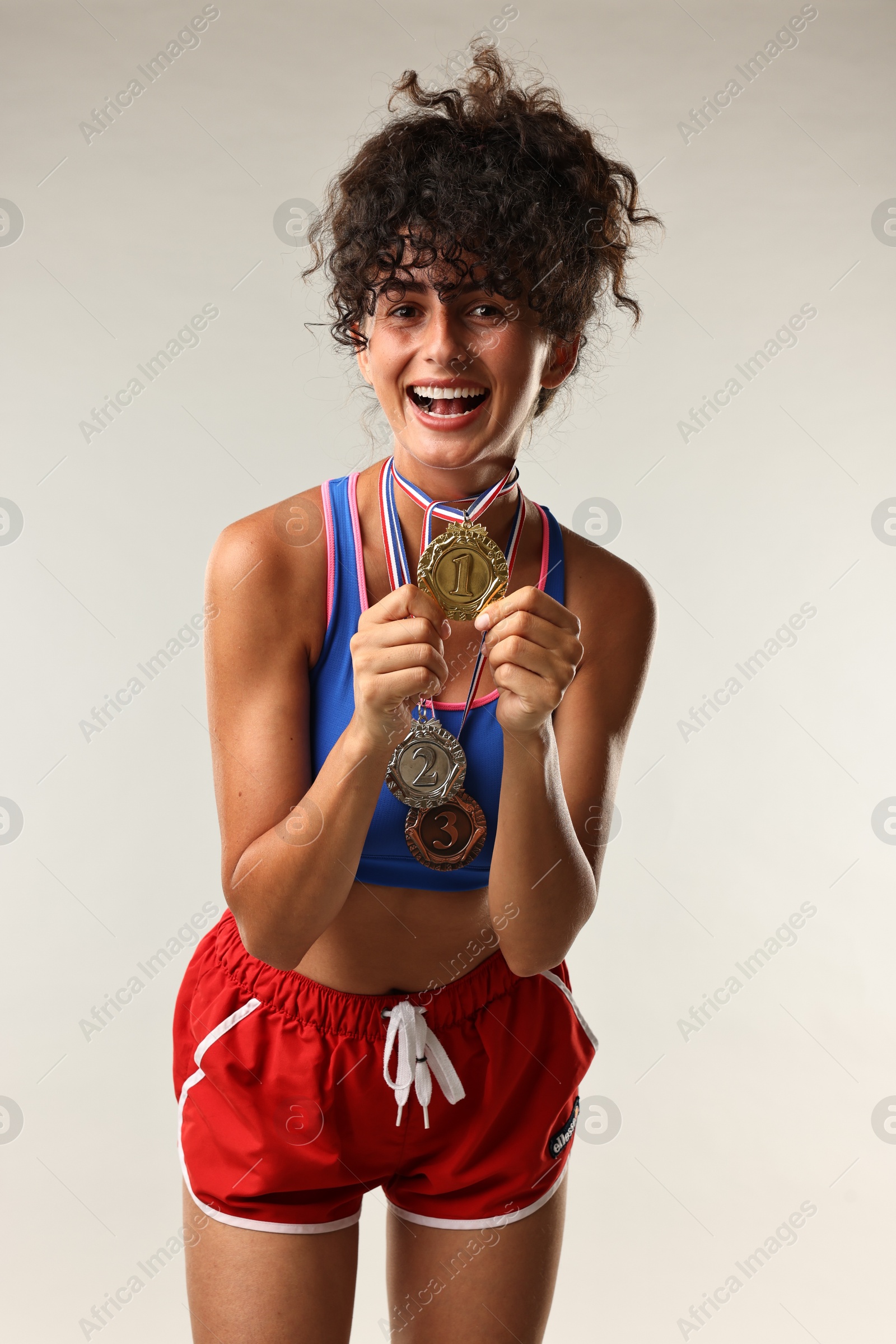 Photo of Happy winner with different medals on light grey background