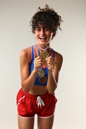 Happy winner with different medals on light grey background