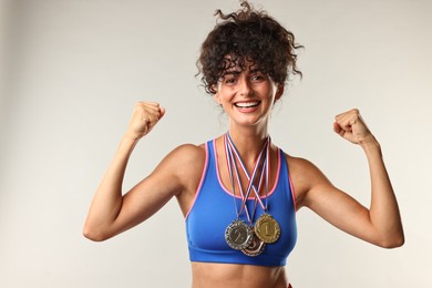 Photo of Happy winner with different medals on light grey background