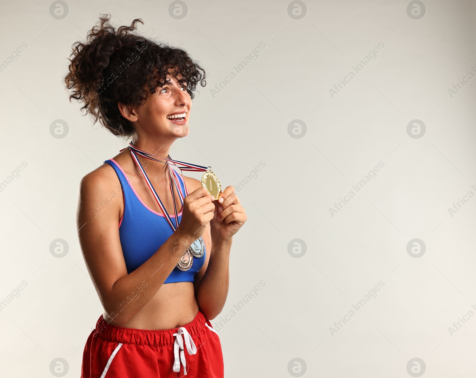 Photo of Happy winner with different medals on light background. Space for text