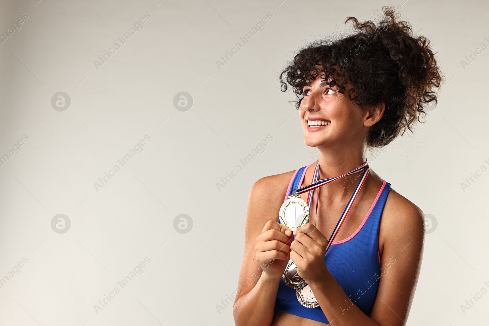 Photo of Happy winner with different medals on light background. Space for text