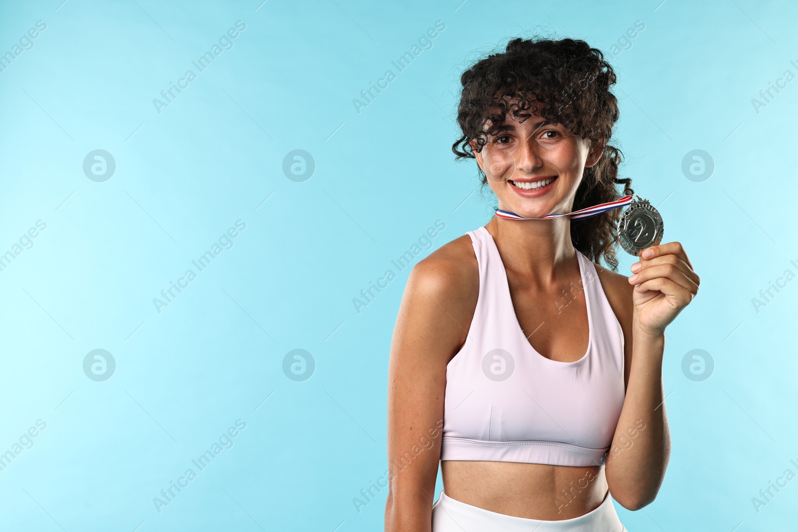 Photo of Happy winner with silver medal on light blue background. Space for text