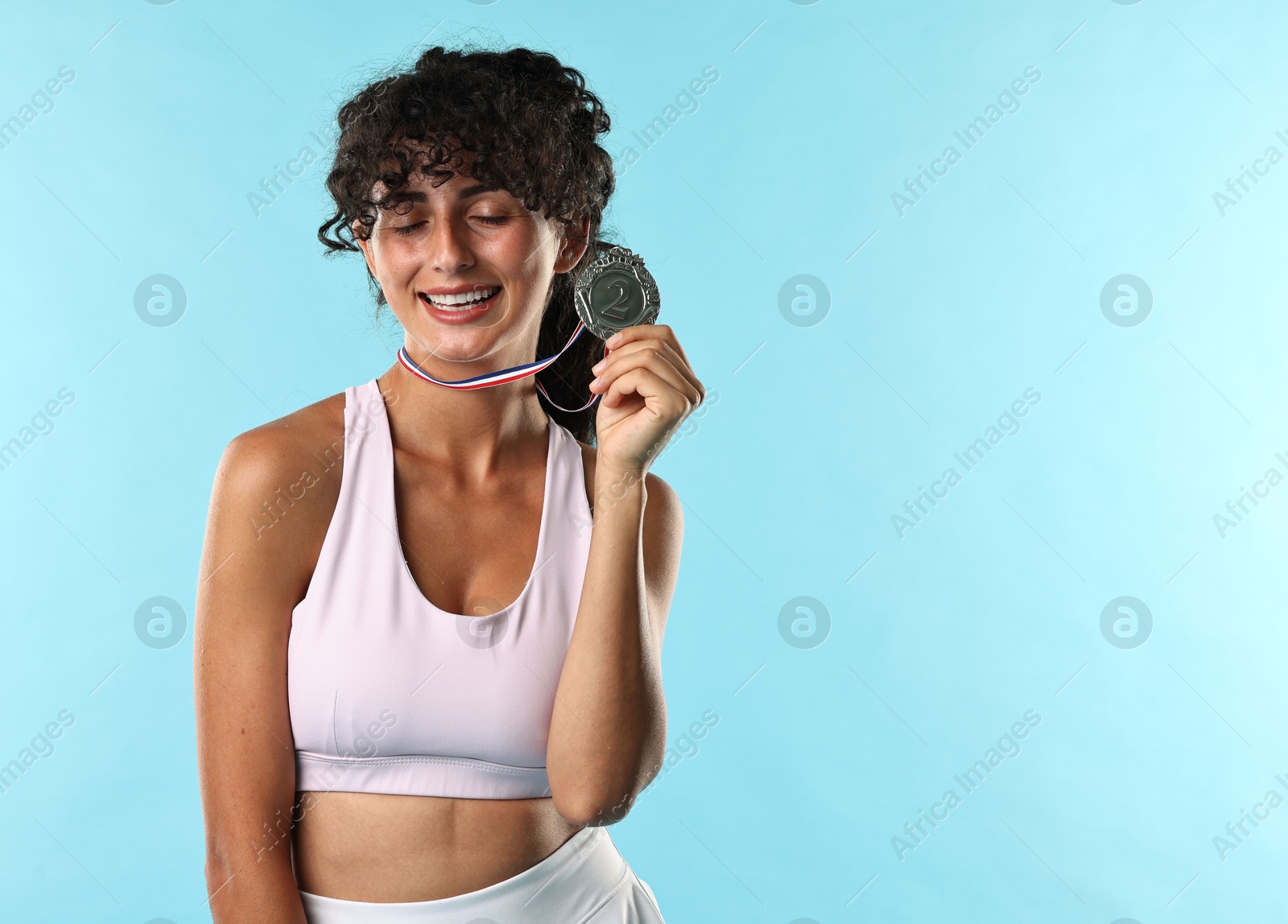 Photo of Happy winner with silver medal on light blue background. Space for text