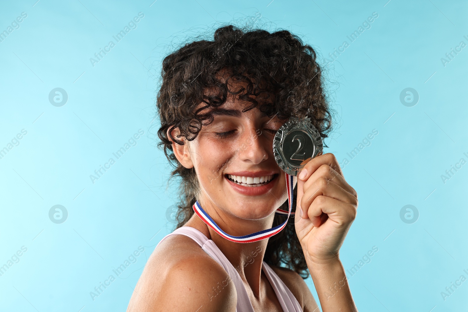 Photo of Happy winner with silver medal on light blue background, closeup