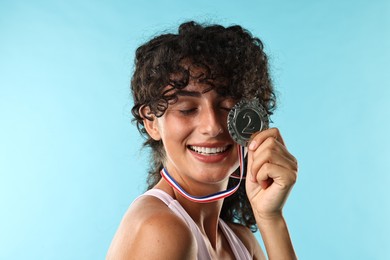 Photo of Happy winner with silver medal on light blue background, closeup