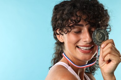 Photo of Happy winner with silver medal on light blue background, closeup. Space for text