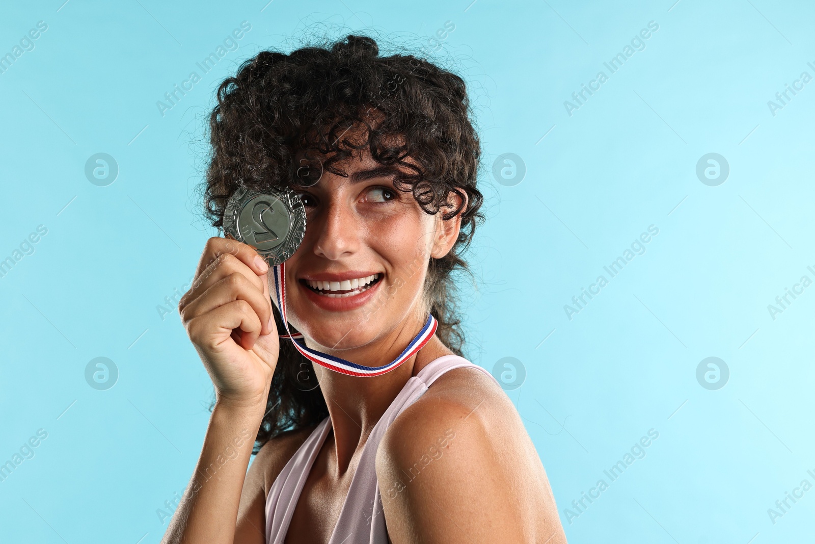 Photo of Happy winner with silver medal on light blue background, closeup